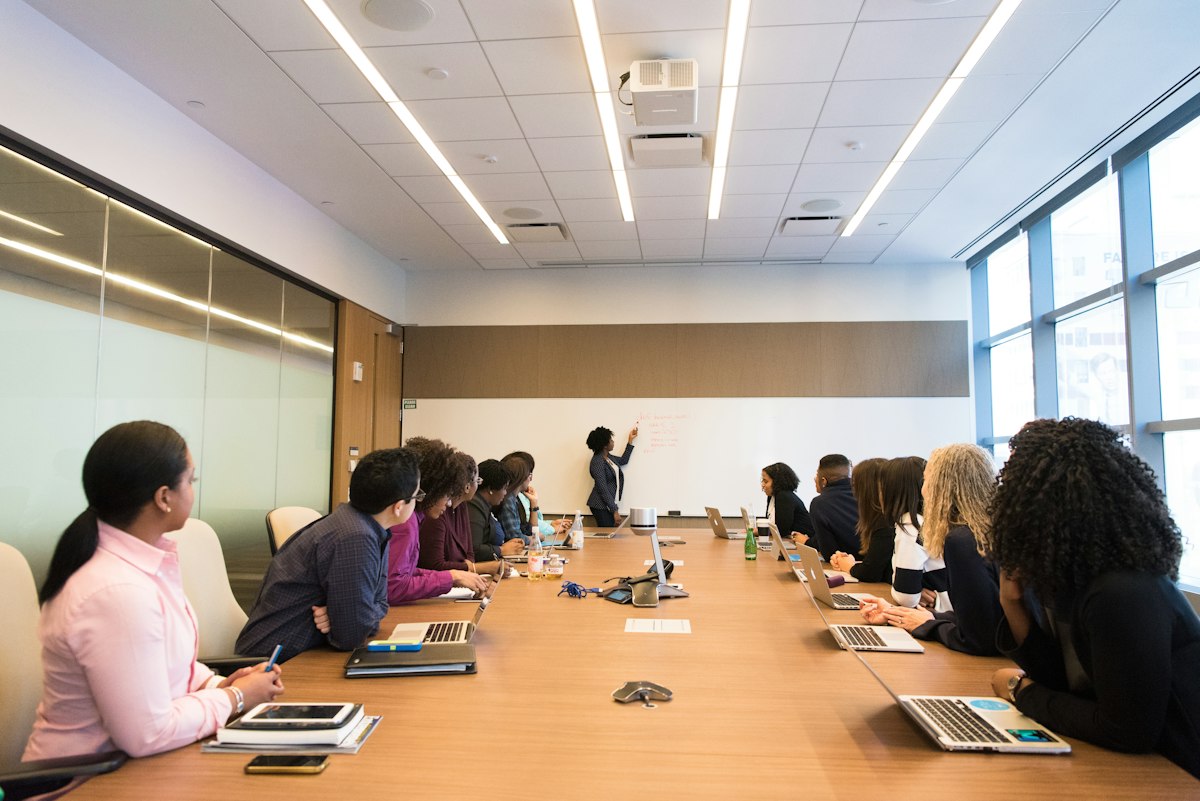 Teilnehmende arbeiten mit Laptops und besprechen Ideen am Whiteboard – Symbolfoto